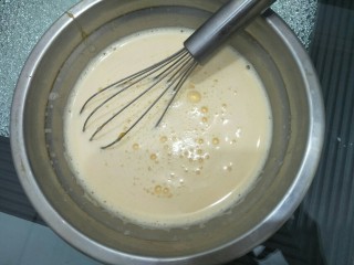 拉花半熟芝士蛋糕,将煮好的牛奶倒入蛋黄糊中搅拌均匀。