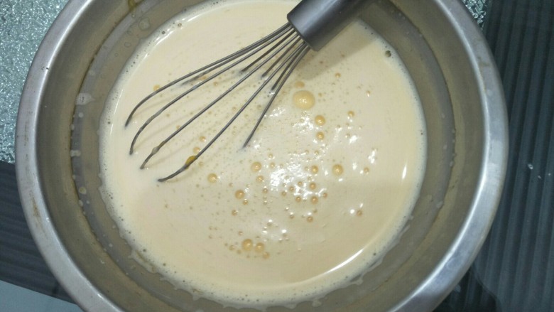 拉花半熟芝士蛋糕,将煮好的牛奶倒入蛋黄糊中搅拌均匀。