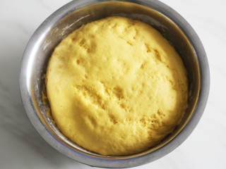 蓬松暄软的奶香胡萝卜馒头,面团发好以后，面板撒上干面粉，取出面团揉一下排出气体再进行二次发酵。