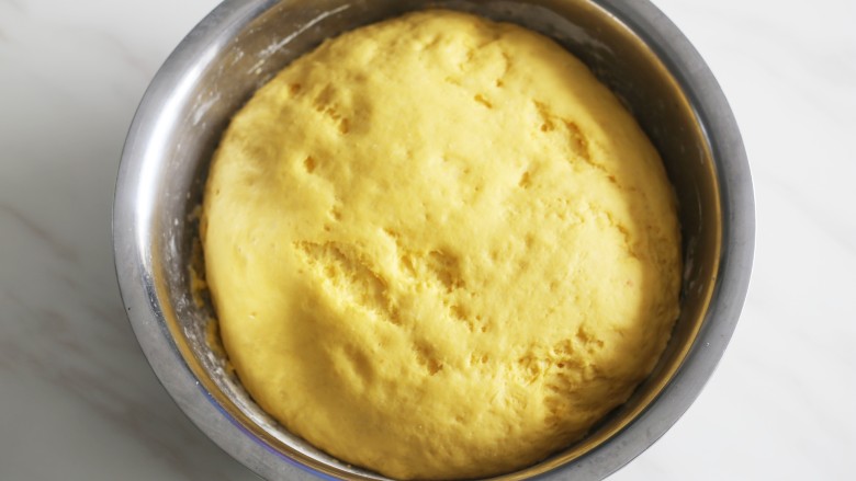 蓬松暄软的奶香胡萝卜馒头,面团发好以后，面板撒上干面粉，取出面团揉一下排出气体再进行二次发酵。