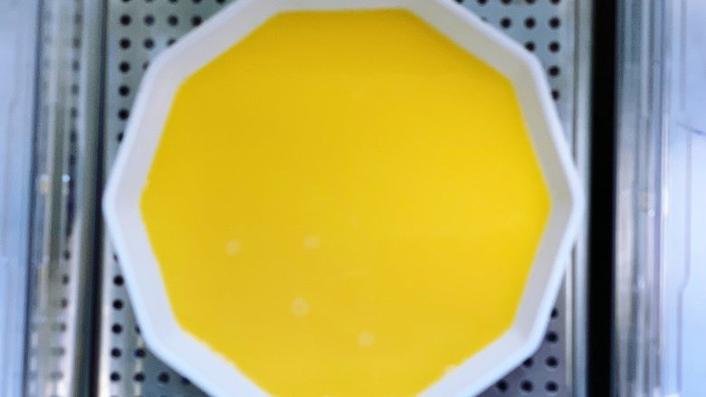 虾仁蒸蛋,表面盖上保鲜膜，用牙签戳几个洞，也可以盖一个盘子，放入臻米电蒸锅的蒸盘上，盖上盖子，定时8分钟，开始蒸蛋。