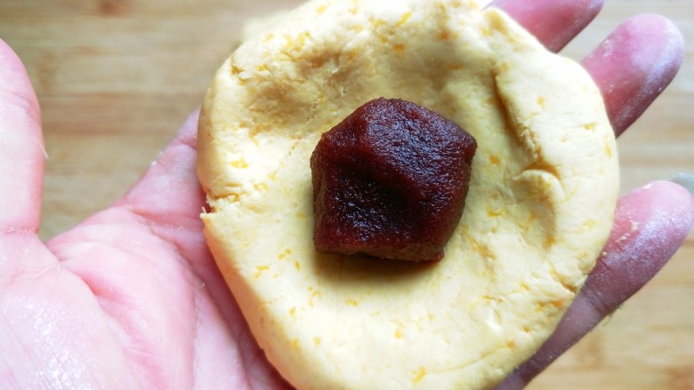 芝香南瓜饼,取一块糯米团，压扁，包上豆沙。