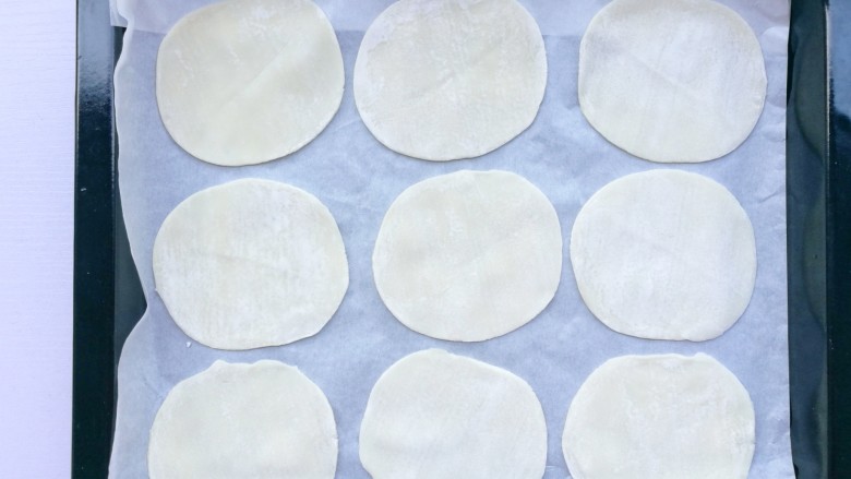饺子皮葱油孜然薄脆饼,饺子皮摆在铺好油纸的烤盘中。
