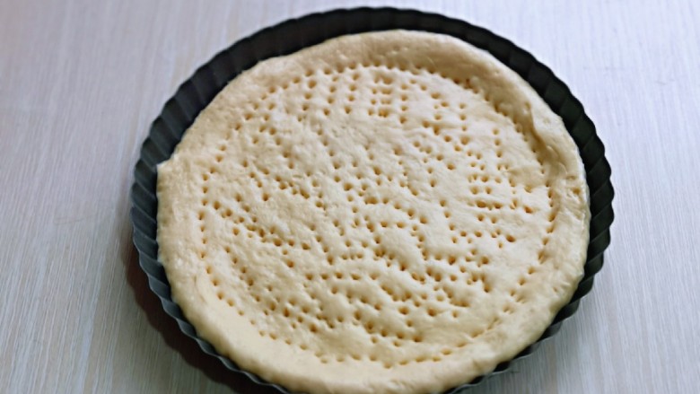 罗勒意式披萨,取一款面团用擀面杖擀圆饼，与自己的披萨盘一样大小即可，再用食品叉子叉满洞洞眼，如图。