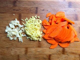 胡萝卜芦笋炒鱿鱼,胡萝卜刮掉外皮，切成薄片，蒜头去皮清洗干净切末，生姜去皮清洗干净切末待用。