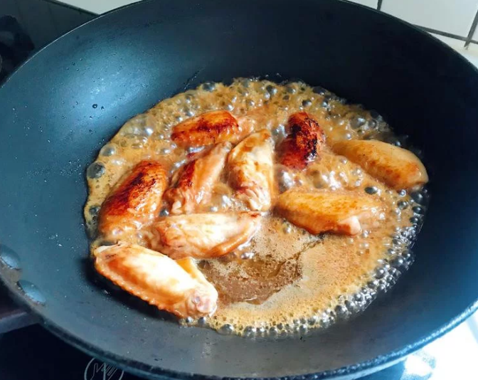 照烧鸡翅,中火烧热锅，将醃鸡翅的酱汁倒入，煮热后放入鸡翅，转中小火慢煮。煮的时候鸡翅要不时翻面，让两边都能入味。