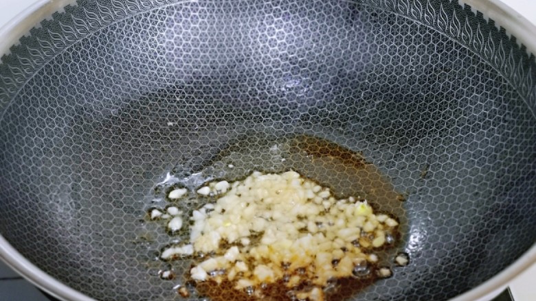 杏鲍菇炒麻辣扇贝肉,锅底留油，加入蒜末炒香。