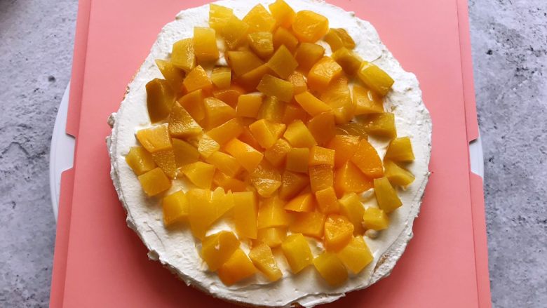 白雪公主蛋糕,用抹刀把淡奶油抹平，上面铺上一层黄桃