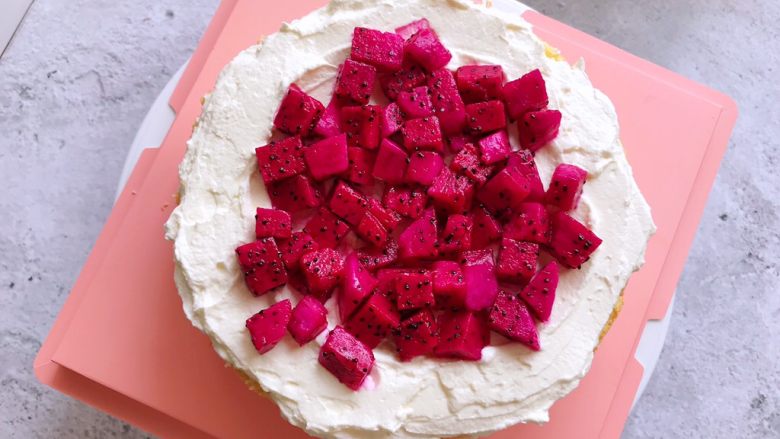 白雪公主蛋糕,用抹刀把淡奶油抹平，上面铺上一层红心火龙果