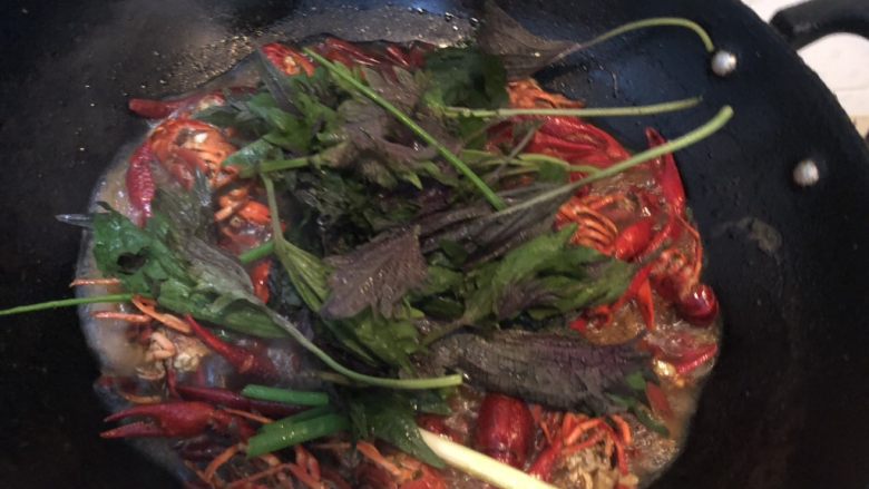 蒜香小龙虾,放入紫苏和葱，继续翻煮一会；