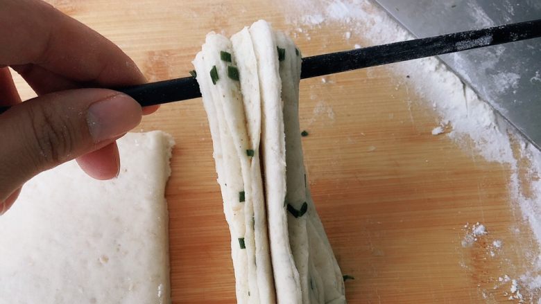 全麦香葱花卷,用筷子从中间提起，右手压住下端捏紧，拿筷子的手转360度