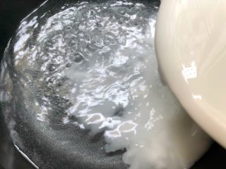 自制凉粉,锅里倒入四碗水，大火把水烧开，烧开以后转中火，把调好的豌豆粉倒入锅里，一边倒一边用筷子快速搅拌。