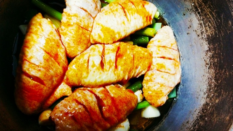 电饭煲奥尔良鸡翅,将腌制的鸡翅放在葱上面，浇上腌制的料汁，中火慢煮