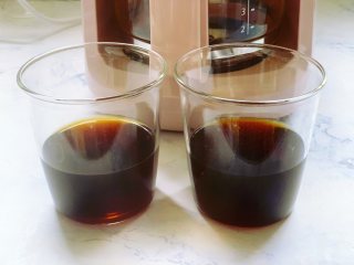 焦糖双色咖啡奶冻,将咖啡液体过筛一遍，分别加到两个提前准备好的玻璃杯里，两杯咖啡的分量要均等。