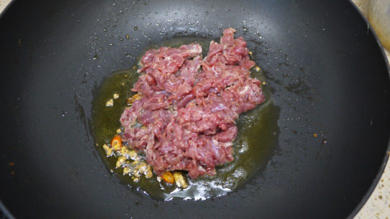 大葱炒牛肉,锅烧热加入适量的橄榄油，然后把大蒜、辣椒放入锅中爆香。然后倒入腌制好的牛肉。