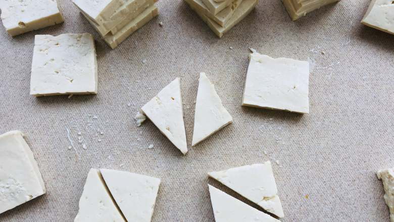 红烧三角豆腐,豆腐改刀切成三角形。先把豆腐切成方形，再改成三角形。切的时候小心不要切破了，改刀成三角形炸起来更加的方便一些。