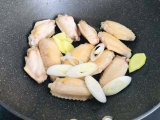 红烧鸡翅,倒入生姜和大葱，和鸡翅一起翻炒出香味