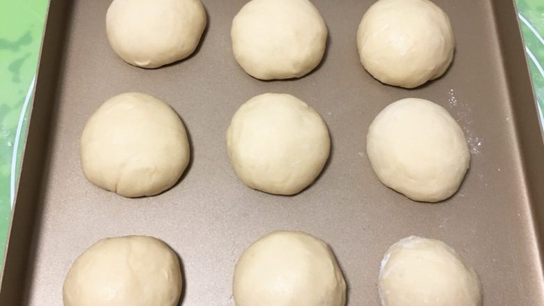 酸奶油椰蓉面包,面团分成九个剂子，盖上保鲜膜静置10分钟，再整理一下移入金盘。