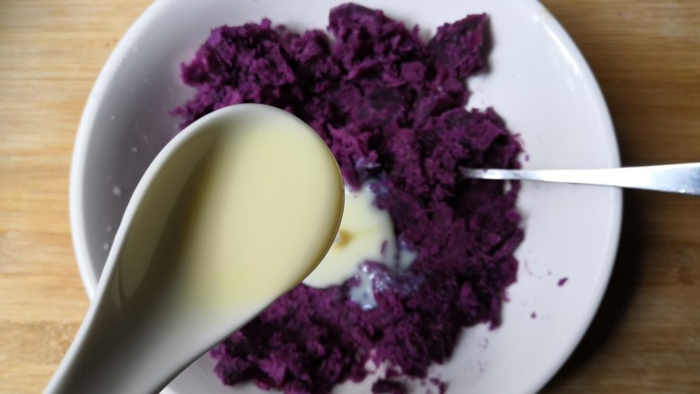 西米紫薯球,把蒸好的紫薯块趁热放入碗中，加入一勺炼奶压成泥。