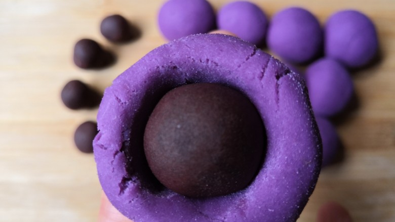 西米紫薯球,拿一个紫薯球，把中间压一个窝，放入豆沙馅，收口撮圆。