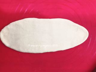 奶香排包,取一个小面团，把小面团擀成椭圆形，借助刮板把面团翻面