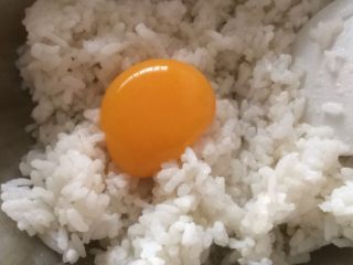 培根杂蔬饭团,熟米饭倒入盆里，放入一个蛋黄，混合均匀；