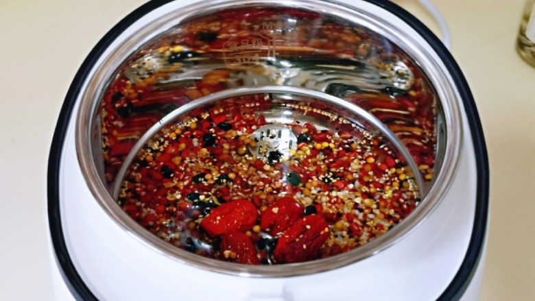 营养谷物杂粮粥,首先将泡好的红豆与杂粮倒入饭煲内胆中。