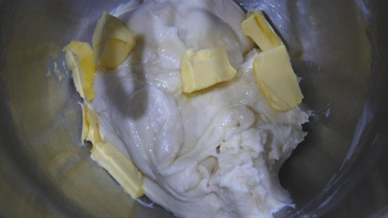 芝士小餐包,然后加入室温软化的无盐黄油，加入黄油后要先用低速搅拌，搅拌至面团把黄油吸收，然后转高速搅拌至面团有延展性，能拉出较薄的膜。