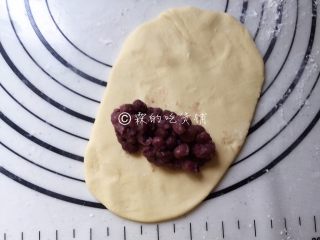 玉米面蜜红豆发面饼,把剂子擀成长面片状，在底部位置放上蜜红豆。