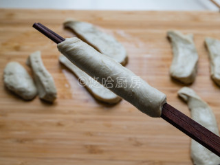 烤面筋,用一双筷子先夹住面筋的一头，一手拉伸拉长面团，一手转动筷子，让面团斜着缠绕在筷子上，最后的面团要抻开抻薄包裹住筷子上的面团，最后就是图中的样子。面团最后不抻薄也可以，直接缠绕就行。