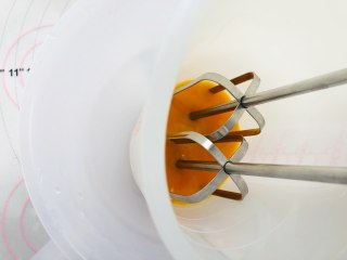 胡萝卜蛋黄溶豆,准备一碗温水，将装蛋黄的容器，放在温水的碗中，隔着温水，使用电动打蛋器中速打发蛋黄。