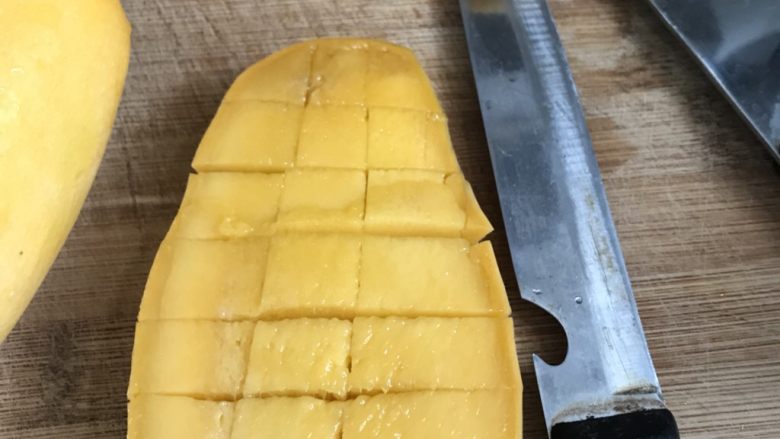 芒果黑凉粉,切成一半用刀划成格子型。