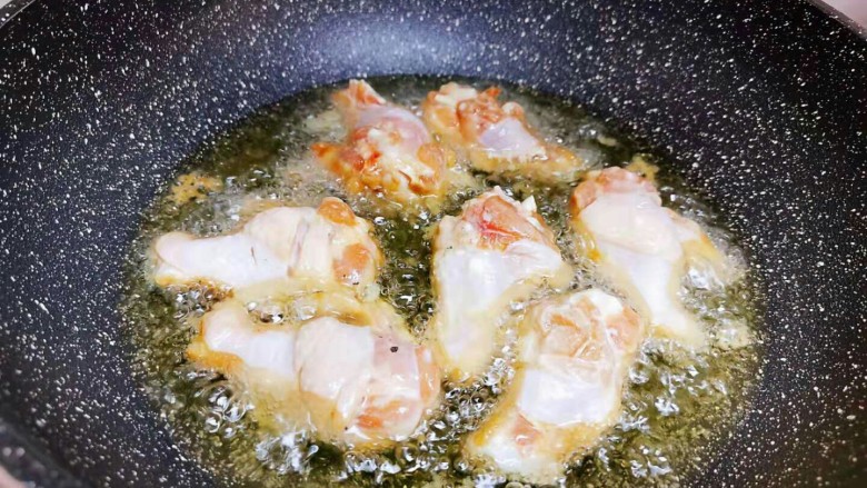 香辣小鸡腿,锅里放入花生油，油热把鸡翅根放下去炸熟。