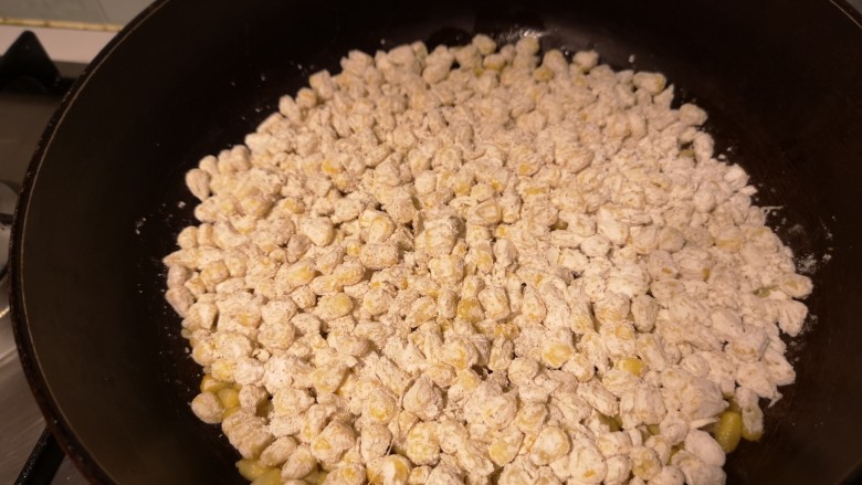 椒盐玉米烙,玉米粒儿倒入平底锅中，用铲刀铺平。