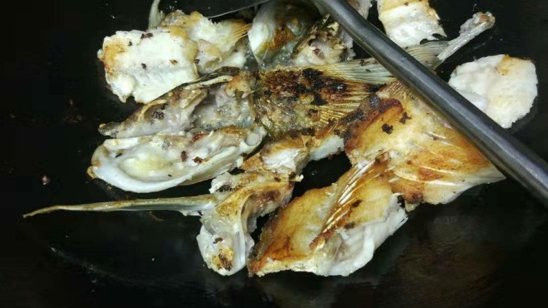 家常版酸菜鱼,鱼头鱼骨腌15分钟后，锅里下油，将鱼头鱼骨鱼尾煎至两面金黄色，上锅备用。