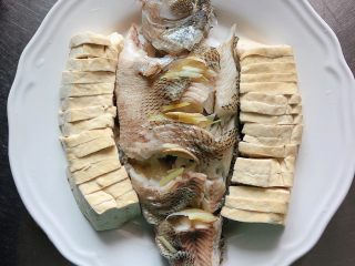 油泼鱼,倒掉盘子蒸出来的汤汁，将鱼和豆腐摆入盘中。