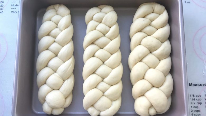 烫种芝麻辫子面包,三份辫子全部编好后，摆放在模具内二次发酵