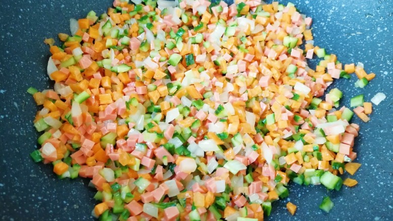 炒杂粮饭,下入胡萝卜、火腿肠和黄瓜丁翻炒均匀。