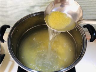 香浓小米南瓜粥,水开后倒入小米，滴入五六滴香油，用勺子搅拌几下，盖上盖子留个缝隙。
