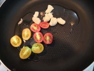 迷迭香黑胡椒牛排,油热，放入小番茄和蒜瓣，煎30秒