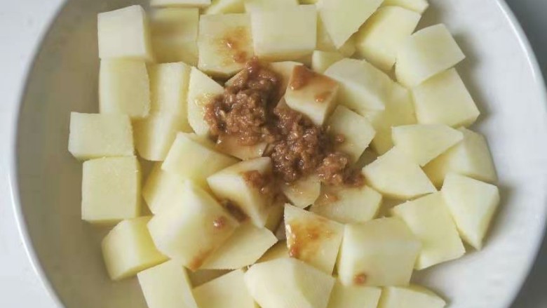 香酥排骨蒸土豆,把刚才排骨料理碗里的剩余酱料和蒜蓉倒进土豆里
