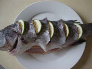 泰式青柠蒸鲈鱼,青柠檬一半切片塞入鱼身的刀口中，