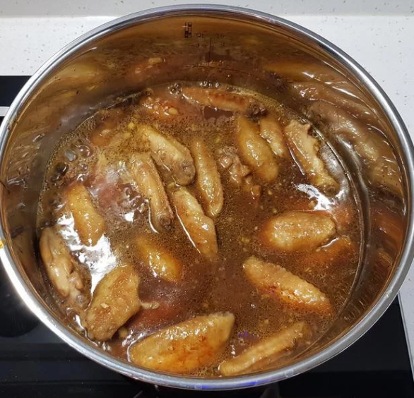 蒜香蜂蜜啤酒鸡翅,加入醃肉酱汁，煮沸后捞除表面浮末。加入煎好备用的鸡翅，盖上锅盖，以中火燜煮20分鐘。