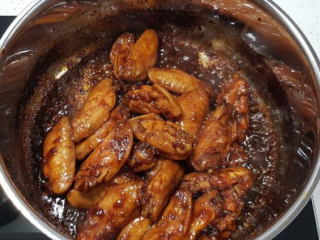 蒜香蜂蜜啤酒鸡翅,打开锅盖，将鸡翅拌炒翻面，继续煮至酱汁收乾，即可关火盛盘。