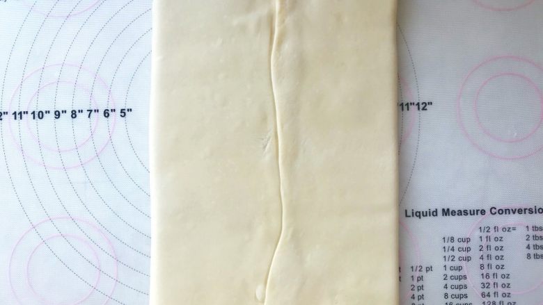 手撕金砖吐司,将两侧的面片向中间对折，接口处捏紧，将黄油包裹好，松弛1分钟