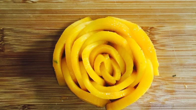 芒果香蕉奶昔,将芒果薄片小心的紧密的围在一起。小片的卷起来做花心，依次从小片到大片的紧密围在一起，成一朵玫瑰花型。