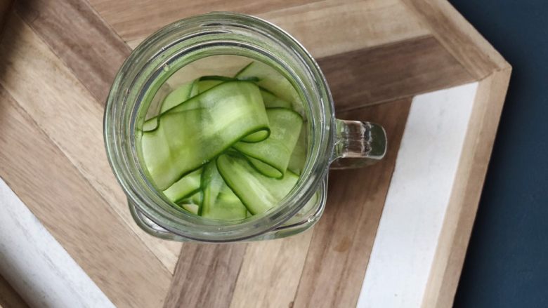 夏日清爽黄瓜水🥒高颜值清暑解渴神水,把削好的黄瓜片放入玻璃器皿。