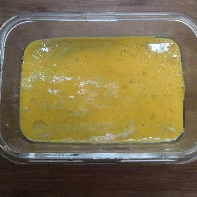 西兰花玉米鸡肉糕,把蛋黄液倒在鸡肉蔬菜泥上面，用刷子刷均匀