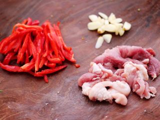菜心红椒炒肉片,把猪肉洗净后切成薄片，红椒切丝，大蒜去皮切片。