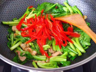 菜心红椒炒肉片,看见菜心断生变软的时候，加入红椒丝。
